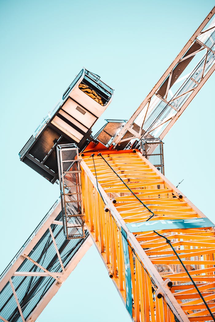 why-choose-us A striking low angle shot of a vibrant yellow tower crane against a clear sky, showcasing industrial power.