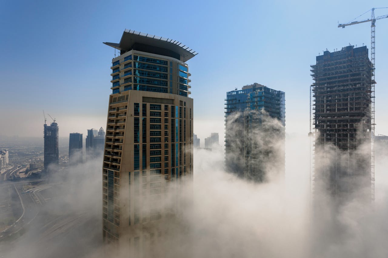 mobile-02 A foggy Dubai skyline with modern skyscrapers emerging above the mist during daylight.
